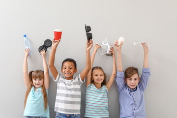 Little children with different trash on light background. Concept of recycling