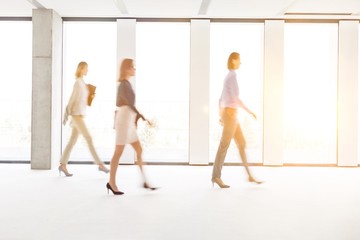 Fototapeta na wymiar Defocused image of businesswomen walking in empty workspace
