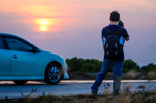 Tourists take pictures of the sunset with his car.