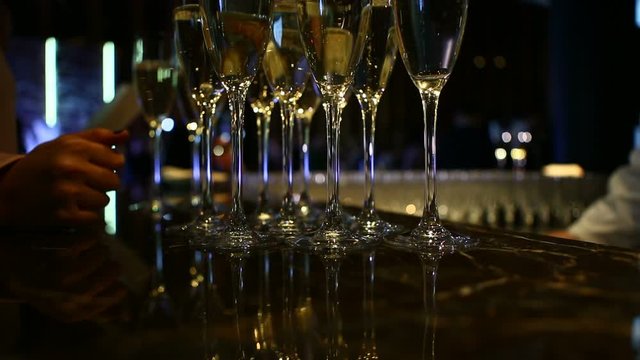 The bartender pours and sets down glasses of champagne