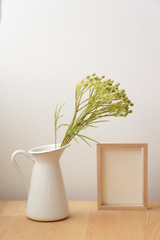 小さな白い花瓶の花と写真立て　木製　木目　フォトフレーム　花瓶　白　ナチュラル　緑　植物　花　葉　自然　観葉植物　部屋　室内　空間　背景　余白　ホワイトスペース　文字スペース　コピースペース