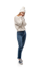 attractive woman posing in jeans, white knitted sweater and hat, isolated on white