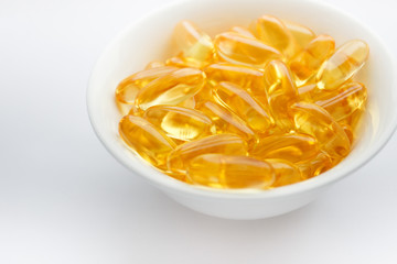 Dietary supplementation. Capsules of fish oil in the white bowl, light background