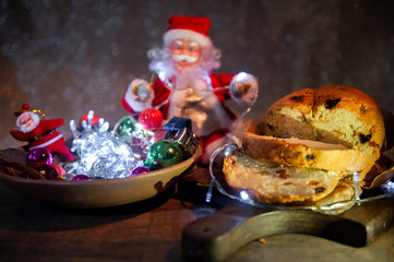 Fototapeta na wymiar Christmas light with Santa Claus in the blurred background. Foreground, panettone, decorating Brazilian Christmas table. Selective focus. Dark background. Close view.