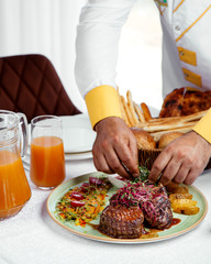 chef serving grilled beef steaks with fries, ketchup and salad