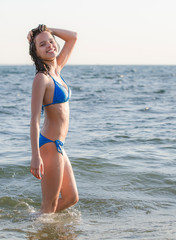 Portrait of a dark-haired wet laughing woman teen in a swimsuit on a summer evening in the light of the setting sun. Copy space