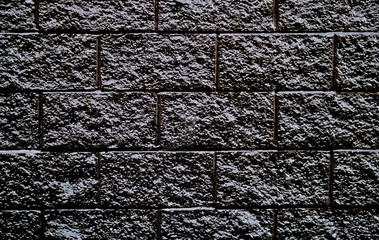 Black painted brick wall rough textures dark background stone, closeup detail grout pattern background image.