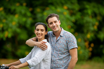 Outdoor shot of young couple in love joyful in the park through grass field. Man and woman hugging and  Laugh on grass field.