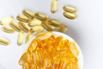 Dietary supplementation. Capsules of fish oil in the white bowl, light background