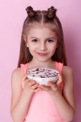 Health & Beauty. Portrait of a littl girl with a granola. Little  girl having breakfast.  Fresh granola, muesli with yogurt in little girl's hands. Granola. Morning. Breakfast. Healthy Diet Nutrition
