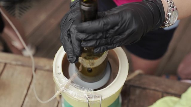 Girl artisan making handmade. Glassworks glass manufacturing process. Glass rolling on the marver. Bottles during the process of brewing handmade