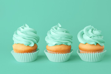 Tasty cupcakes on color background