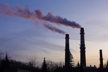 Steaming industrial chimneys at dawn. Winter frosty morning
