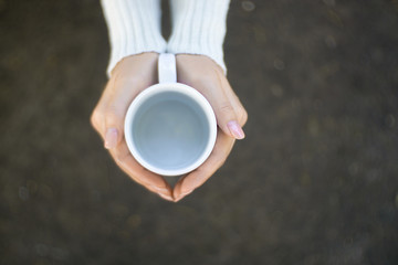 Female hands holding cups of coffee.
