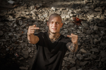 Young brutal bald tattooed guy with both hands shows his middle fingers. A handsome guy shows rude...
