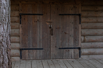 Old wooden gate of a rustic barn. Wooden gate with metal hinges, padlock and wooden latch. Entrance to an old rural village shed