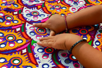 Obraz na płótnie Canvas embroidery mirror work on little baby hand,traditional embroidery in Gujarat,handmade ahir embroidery,India embroidery