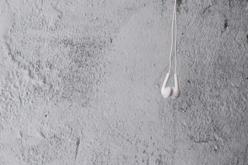 White earphone hanging on grey background