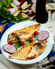 half-cut grilled fish served with onion and cherry tomato