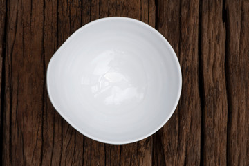 Empty ceramic white bowl on wooden background. Top view of egg shape