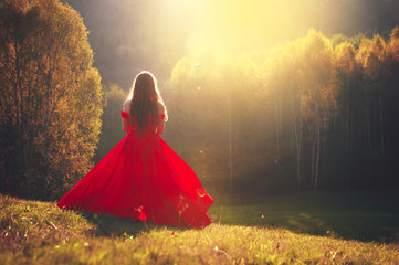 Beautiful young girl in a red dress in Fantastic autumn nature. Fashion photo