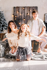 Christmas and new year theme. Parents and children at home playing with fake snow. Laughing joyful & emotions. Christmas 2020. The family catches snow.
