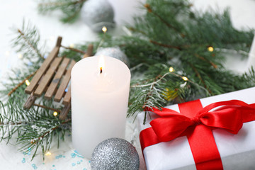 Glowing candle with Christmas decor and gift on white background