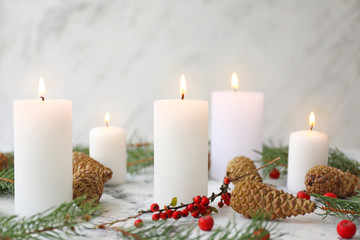 Glowing candles with Christmas decor on white background