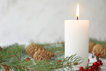 Glowing candle with Christmas decor on white background