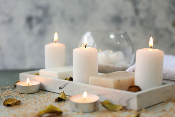 Glowing candles with soap on table
