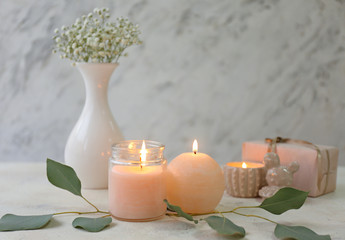 Glowing candles with eucalyptus on table