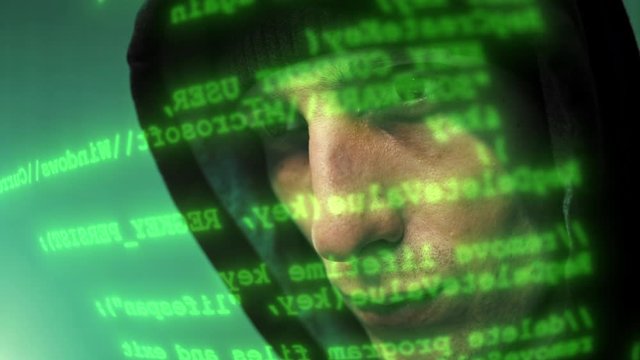 Close-up of the hacker working on a computer while green code characters running infront of his face in a dark office room. 4K (UHD)