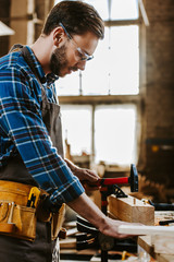 side view of carpenter holding hammer in workshop