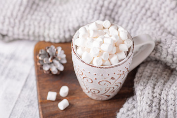 Fototapeta na wymiar Mug with coffee and marshmallow, sweater, cinnamon. Cozy christmas composition. Hygge concept Soft focus