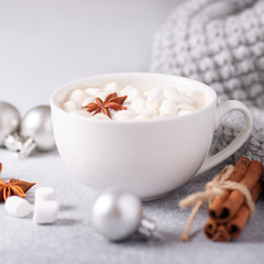 White cup with coffee and marshmallow, sweater, cinnamon. Cozy christmas composition. Hygge concept Soft focus