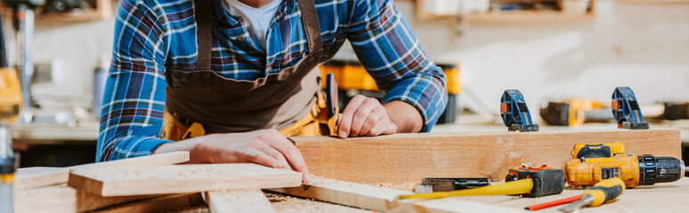 panoramic shot of carpenter touching wooden dowel
