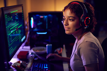 Fototapeta na wymiar Female Teenage Hacker Sitting In Front Of Computer Screens Bypassing Cyber Security