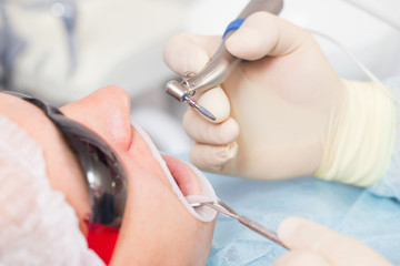 Male patient undergoing implant surgery in a dental clinic. The dentist holds a drill with an implant.