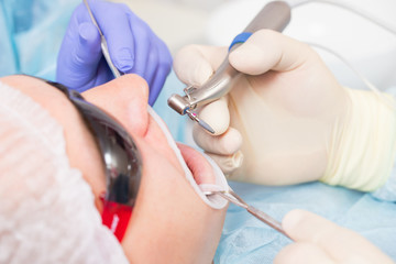 Male patient undergoing implant surgery in a dental clinic. The dentist holds a drill with an implant.