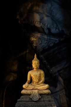 A peaceful Golden Buddha statue superimposed and double exposured with Wheel of Dhamma. Buddha statue from Wat Pathum Wanaram, Bangkok, Thailand, is posing “The attitude of subduing Mara".