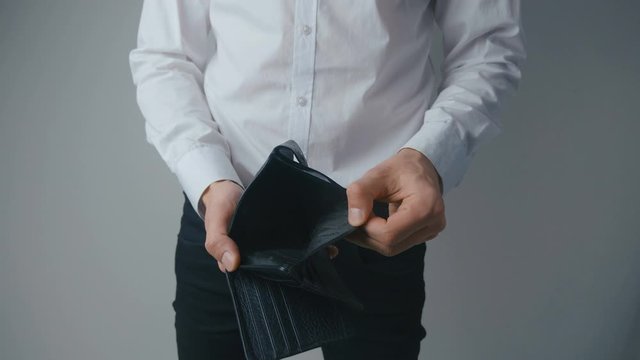 Businessman's hands showing empty lether wallet with no money. Concept of personal or business bankruptcy, financial crisis, loans and debts, shortage of funds.