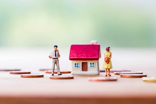 selective focus of miniature angry woman with miniature man and mini house,stack coins on wooden  background for Asset management after divorce concept.
