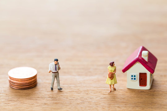 selective focus of miniature angry woman with miniature man and mini house,stack coins on wooden  background for Asset management after divorce concept.
