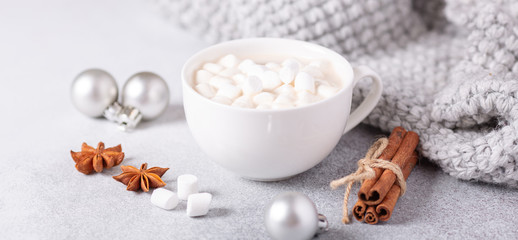Fototapeta na wymiar White cup with coffee and marshmallow, sweater, cinnamon. Cozy christmas composition. Hygge concept Soft focus