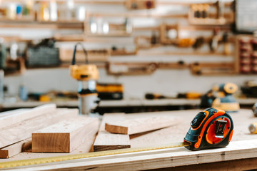 selective focus of measuring tape near wooden planks on table