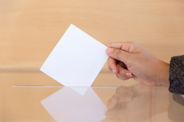 Mano de mujer depositando su voto en una urna