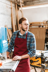 Obraz premium selective focus of handsome woodworker using cnc machine in workshop