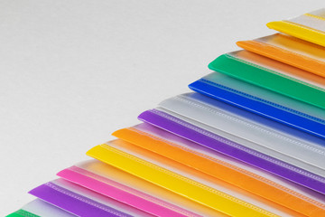 A row of multi-colored plastic folders for paper on a white background.