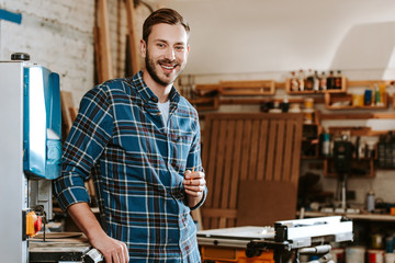 cheerful carpenter holding pencil in workshop