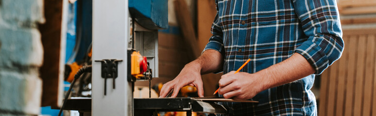 panoramic shot of carpenter holding pencil